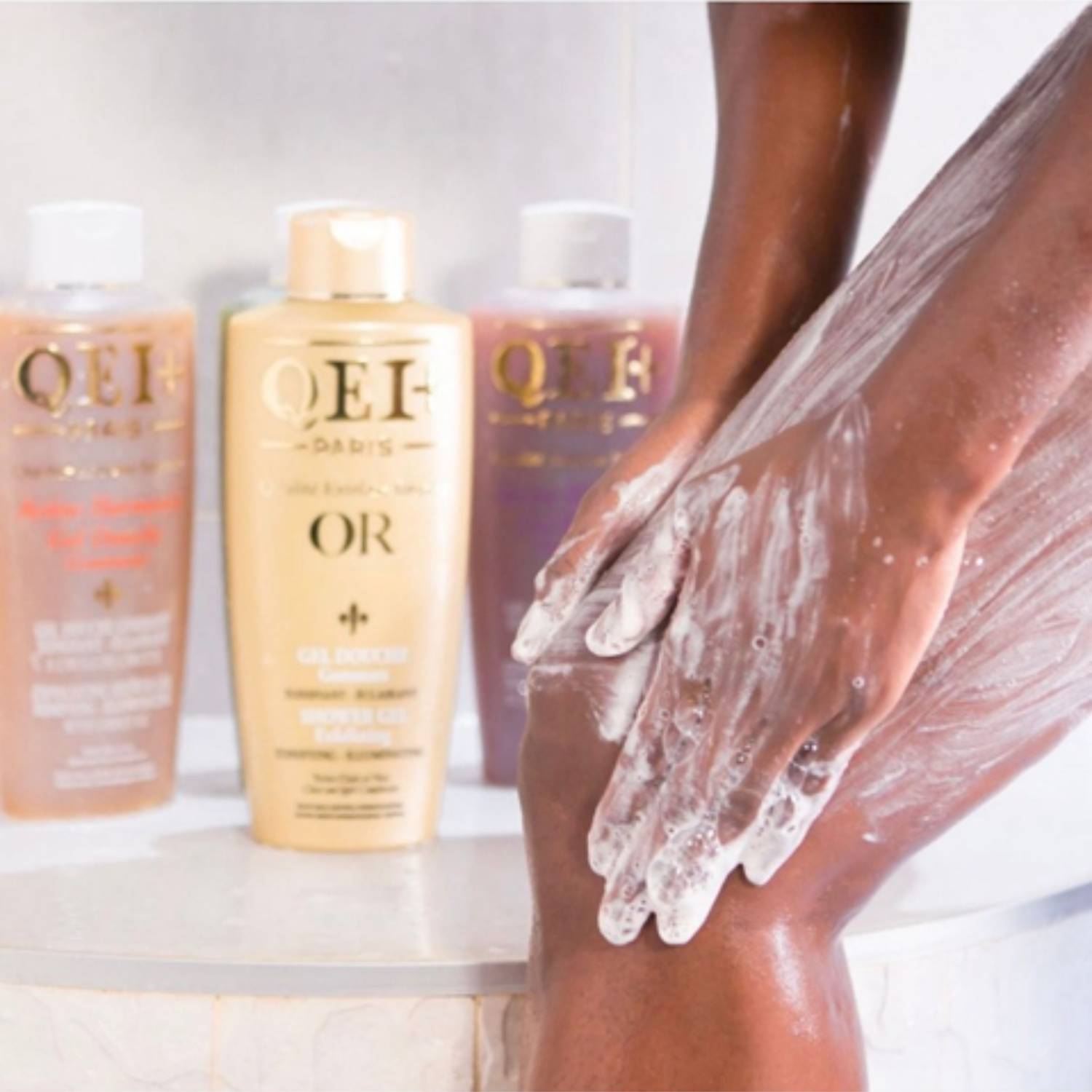 Gels douche gommants QEI+ Paris en mousse sur une peau riche en mélanine